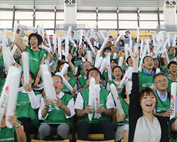 画像　スティックバルーンを使って障害者スポーツ大会で応援する社員の写真