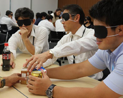 画像　アイマスクをして飲料の容器を触っている場面の写真