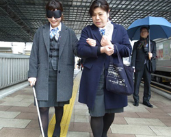 視覚障害者誘導ブロック歩行体験会の様子。アイマスクと白杖を使った歩行体験と、誘導の体験場面の写真