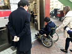 画像　従業員が車椅子に乗車して街のバリアを体験している場面の写真